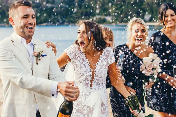 Newlywed couple popping champagne.