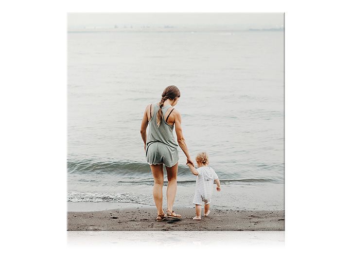 Tela quadrada da mãe e seu filho dando as mãos e mergulhando seus pés na água na praia.