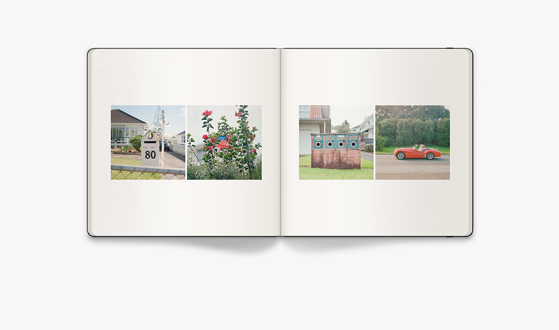 Open Square Moleskine Photo Book with photos of Auckland local street with red car, white letterbox, and red flowers on display