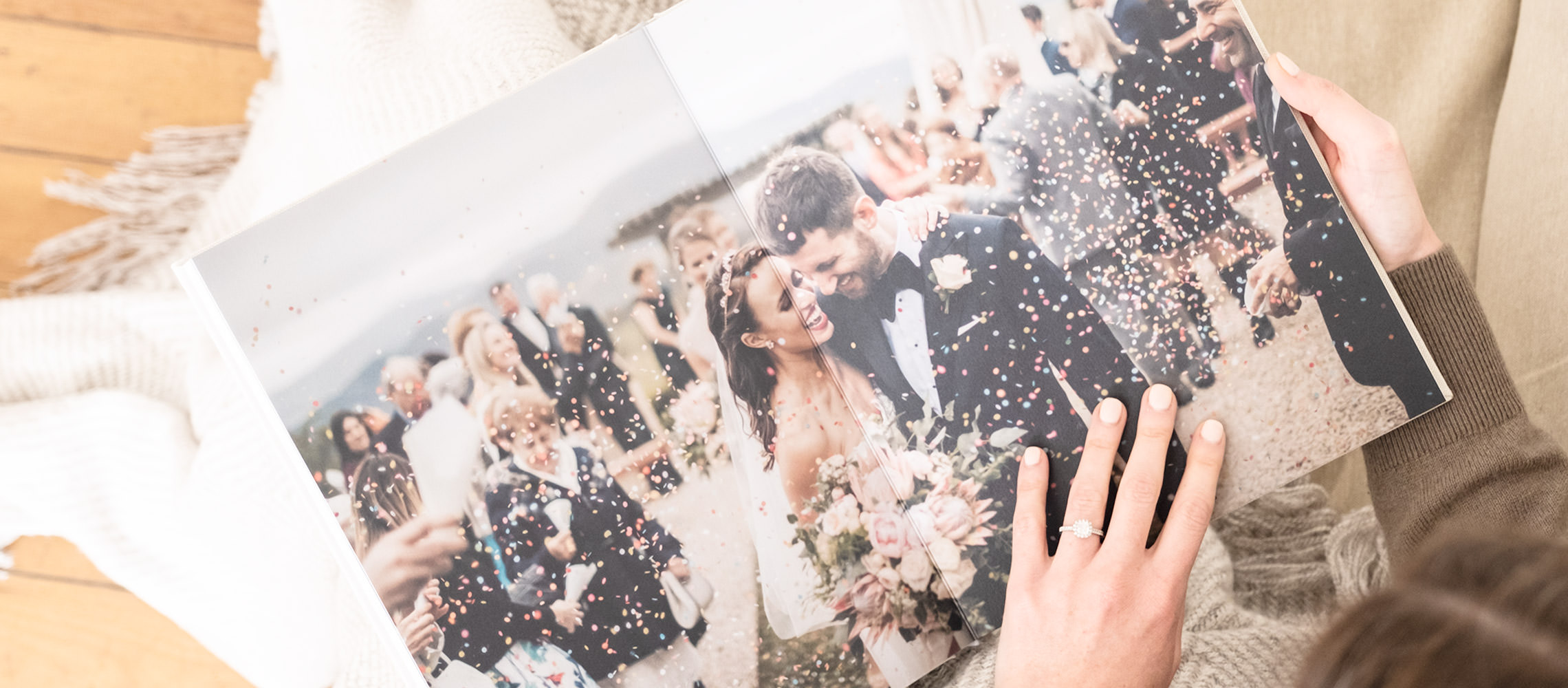 Woman with engagement ring holds open a Portrait Wedding Photo Album with newlyweds on pages