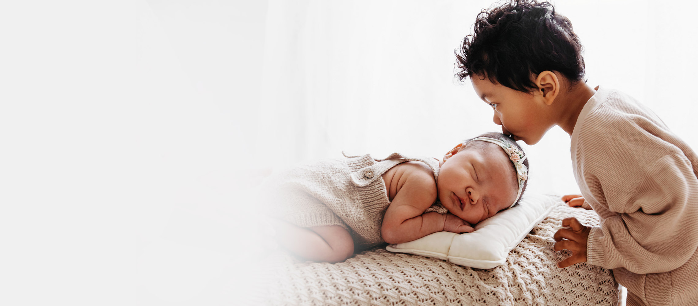 Little boy kissing sleeping baby's head