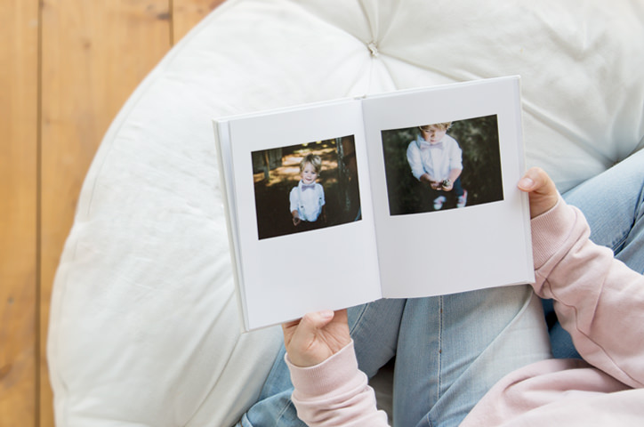 Child holding small portrait photo book while seated